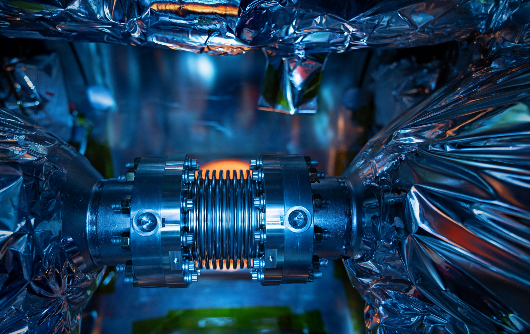 Colored light reflects off metallic surface details of the bellows inside the SNS-PPU cryomodule CM-08 at Jefferson Lab’s SRF Test Lab.