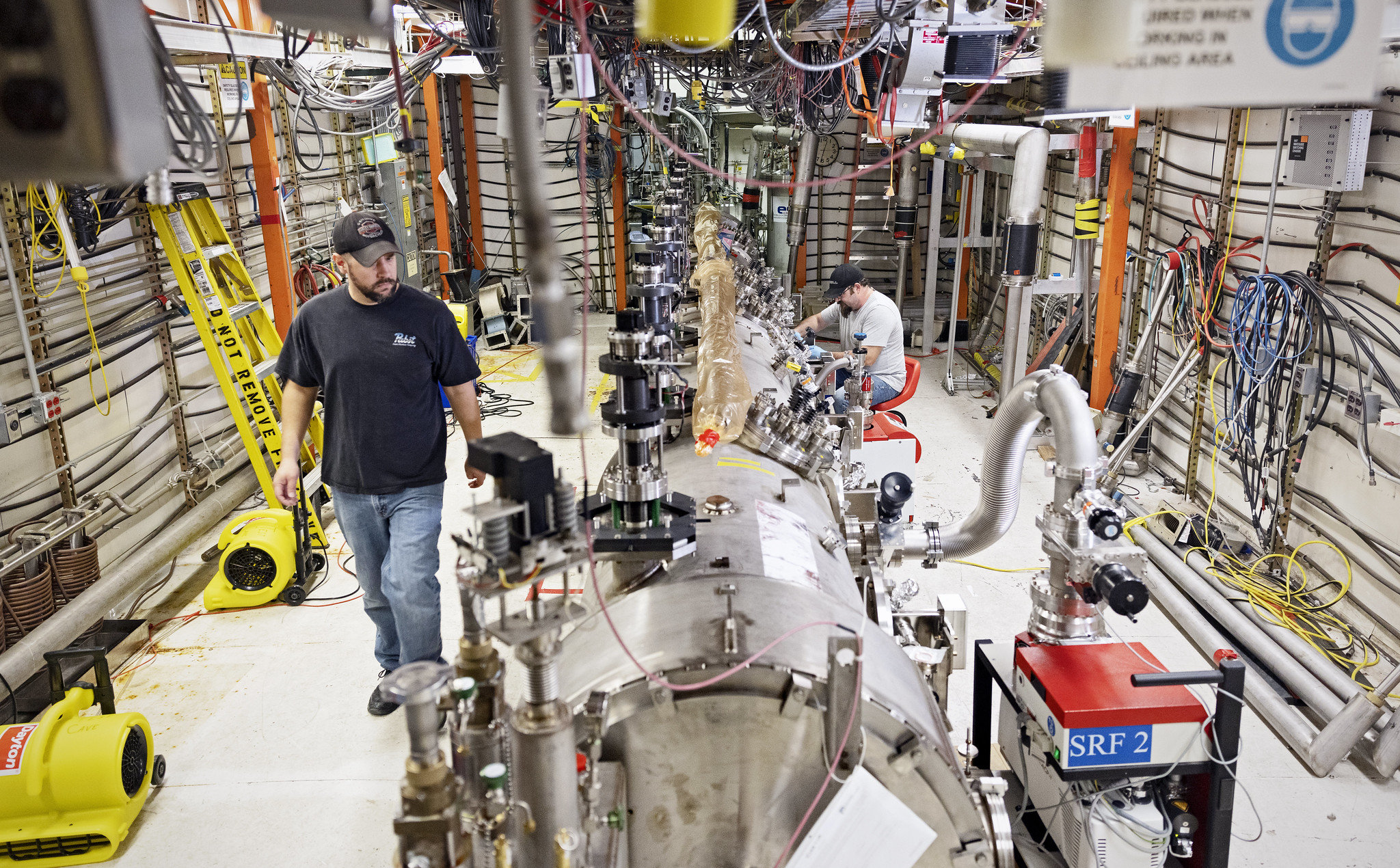 Senior Cryomodule/Vacuum Technician Chris Wilcox, left, and Cryomodule Assembly Technician Cary Light work inside the Cryomodule Test Facility in Jefferson Lab’s SRF Test Lab.