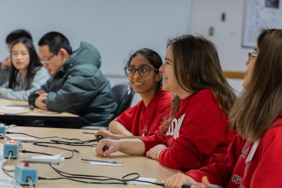 Students at a table, engaged in a Science Bowl competition with electronic buzzers on the tables.