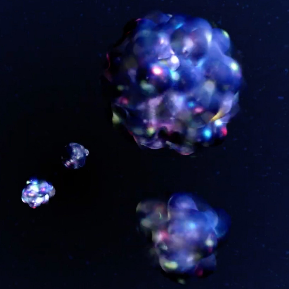 Artist's conception of nuclei, blue-colored nuclei made of spherical protons and neutrons with red, green & blue quarks visible